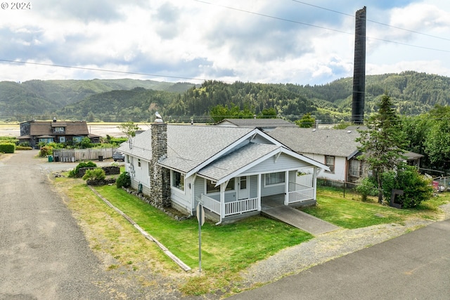 view of front of house with a front lawn, a mountain view, and covered porch