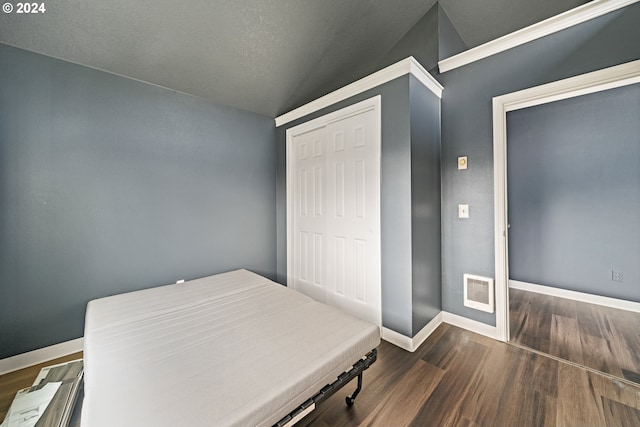 bedroom featuring wood-type flooring, a textured ceiling, and vaulted ceiling