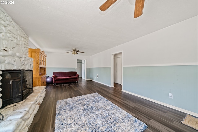 bedroom with ceiling fan, a textured ceiling, a fireplace, and dark hardwood / wood-style flooring