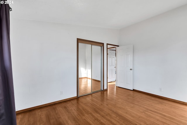 unfurnished bedroom featuring hardwood / wood-style floors, vaulted ceiling, and a closet