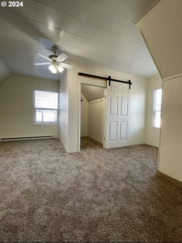 additional living space featuring carpet flooring, a barn door, ceiling fan, and vaulted ceiling