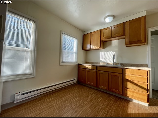 kitchen featuring dark hardwood / wood-style flooring, a baseboard radiator, a healthy amount of sunlight, and sink