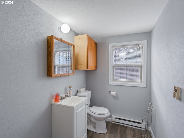 bathroom with hardwood / wood-style floors, vanity, a baseboard heating unit, toilet, and a textured ceiling