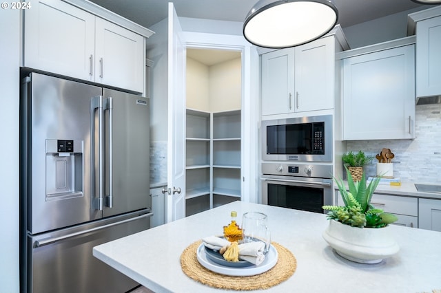 kitchen featuring decorative backsplash, appliances with stainless steel finishes, and white cabinets