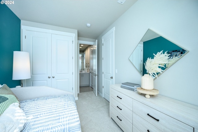 bedroom featuring ensuite bath, light carpet, and a closet