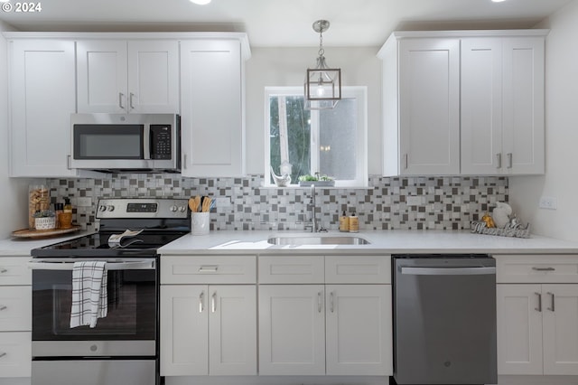 kitchen with appliances with stainless steel finishes, decorative light fixtures, white cabinetry, and sink