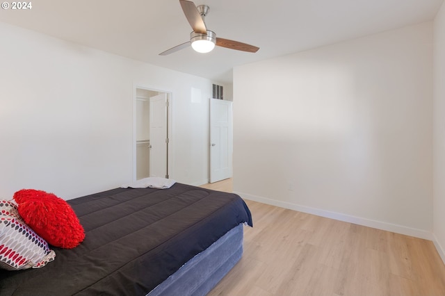 bedroom featuring a closet, wood-type flooring, ceiling fan, and a walk in closet