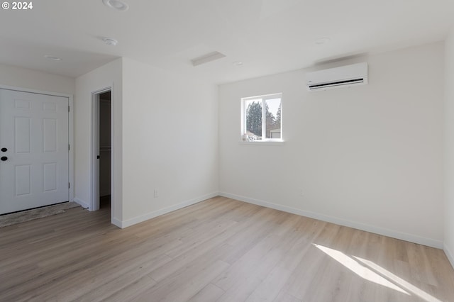 unfurnished room featuring light hardwood / wood-style floors and a wall mounted AC