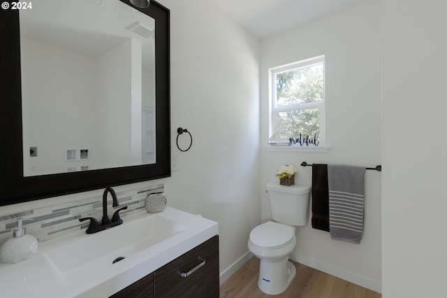 bathroom with wood-type flooring, tasteful backsplash, vanity, and toilet