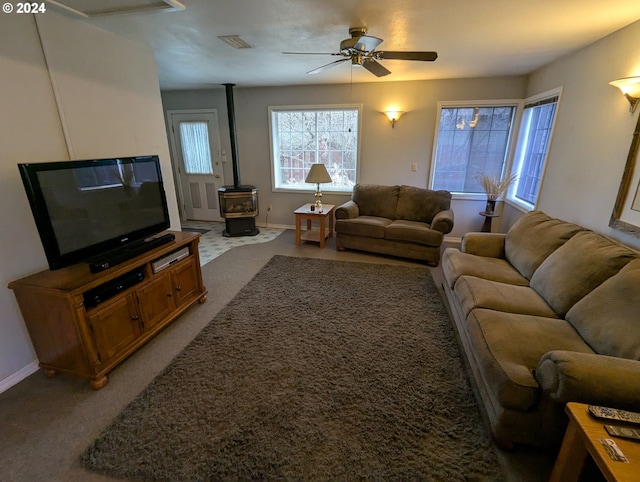 living room with carpet flooring, ceiling fan, and a wood stove