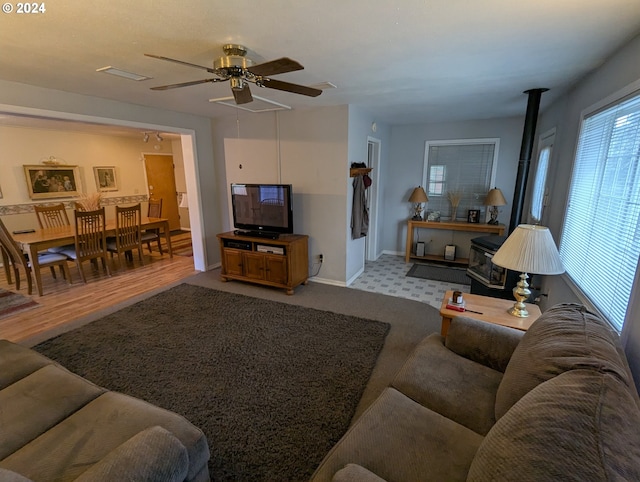 living room featuring a wood stove, ceiling fan, and light wood-type flooring