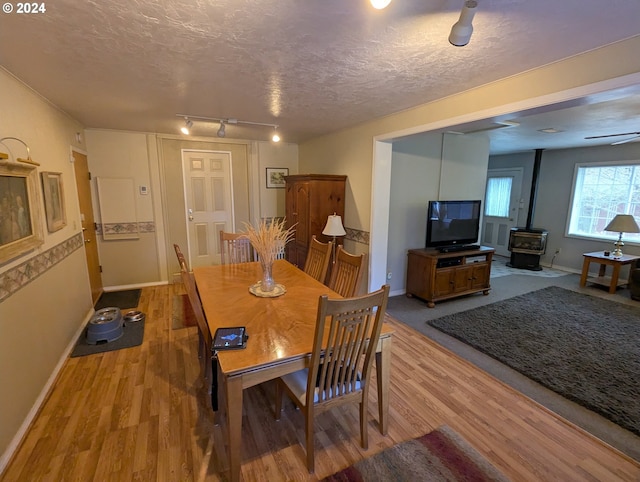 dining space with a wood stove, a textured ceiling, and light hardwood / wood-style flooring