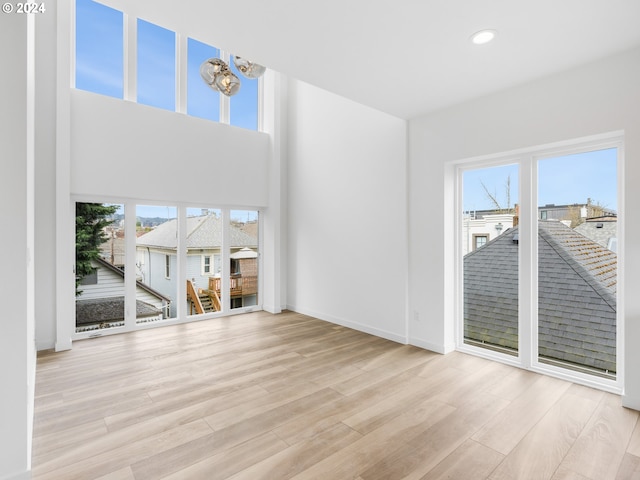 unfurnished living room with a notable chandelier and light hardwood / wood-style flooring