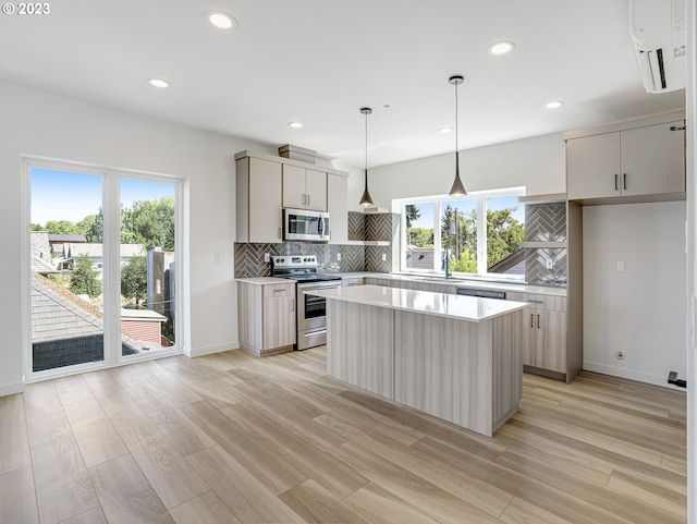 kitchen featuring pendant lighting, light hardwood / wood-style flooring, stainless steel appliances, a center island, and decorative backsplash