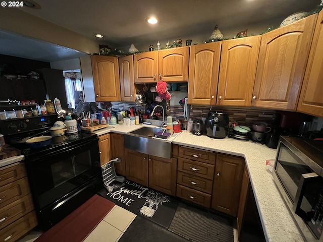 kitchen with black range with electric cooktop, tasteful backsplash, light tile floors, and sink