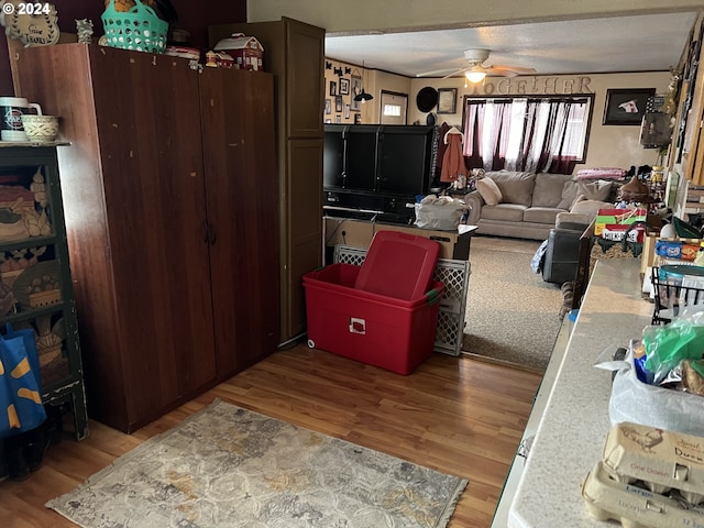 living room with a textured ceiling, ceiling fan, and light hardwood / wood-style flooring