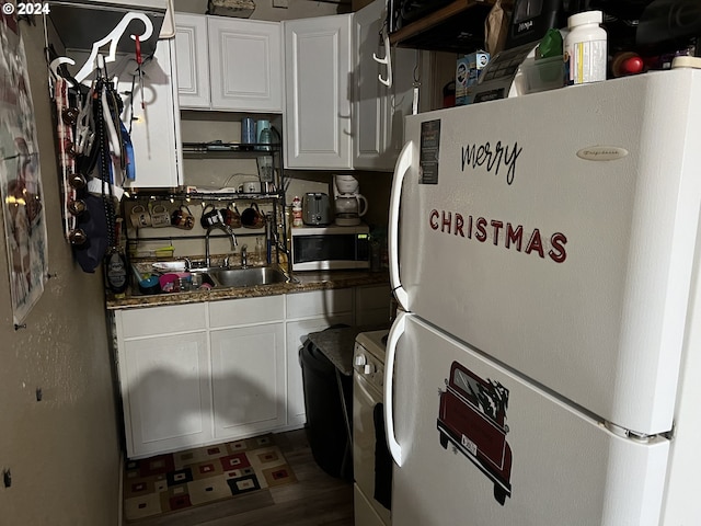 kitchen featuring sink, dark stone countertops, white cabinets, dark hardwood / wood-style flooring, and white refrigerator