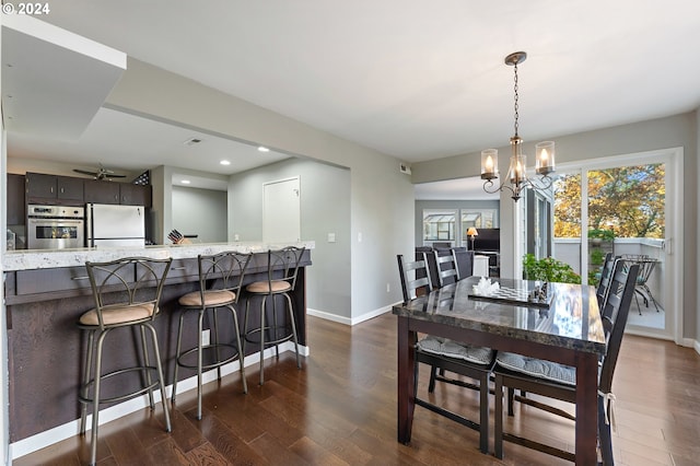 dining space featuring ceiling fan with notable chandelier and dark wood-type flooring