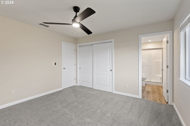 unfurnished bedroom featuring light carpet, connected bathroom, a closet, and ceiling fan