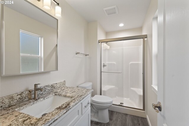 bathroom with vanity, hardwood / wood-style flooring, toilet, and a shower with door