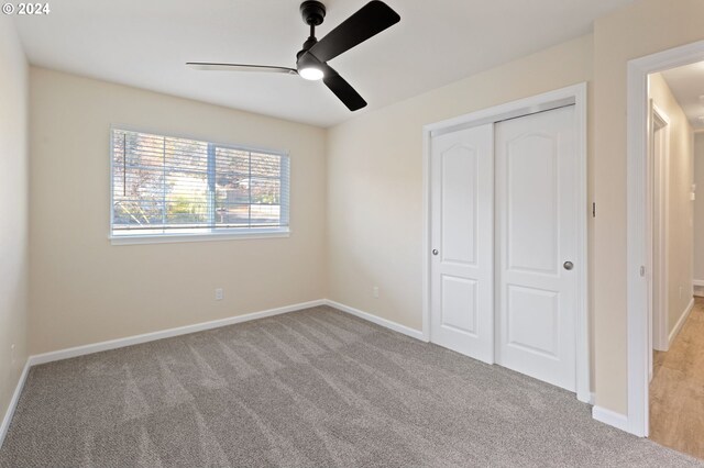 unfurnished bedroom featuring ceiling fan, light colored carpet, and a closet