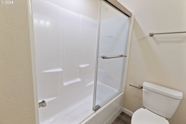 bathroom featuring hardwood / wood-style floors, toilet, and enclosed tub / shower combo