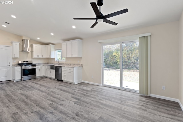 kitchen featuring white cabinetry, wall chimney exhaust hood, light hardwood / wood-style floors, and appliances with stainless steel finishes