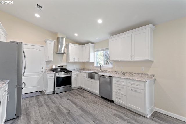 kitchen featuring wall chimney exhaust hood, stainless steel appliances, sink, light hardwood / wood-style floors, and lofted ceiling