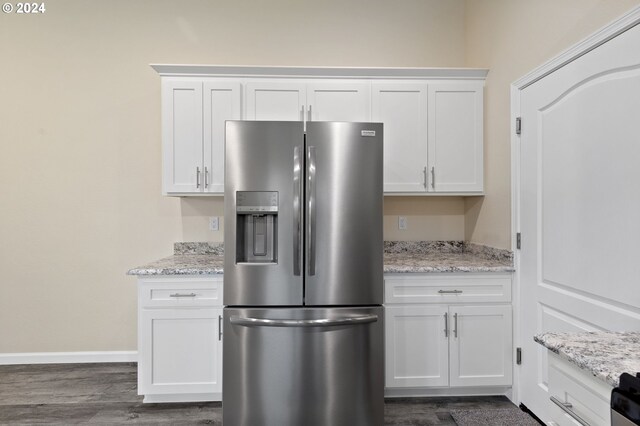 kitchen with white cabinets, stainless steel refrigerator with ice dispenser, light stone counters, and dark wood-type flooring