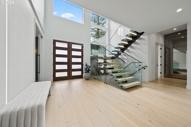 entrance foyer featuring light hardwood / wood-style flooring, a towering ceiling, and french doors