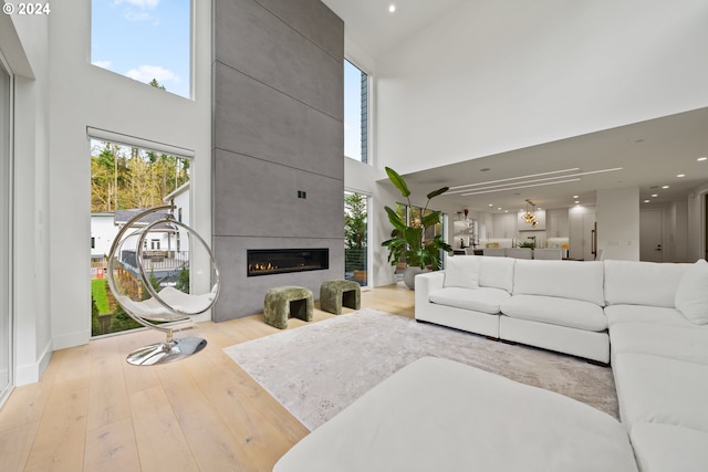 living room with a towering ceiling, light hardwood / wood-style floors, and a fireplace