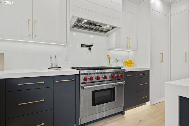 kitchen featuring premium range, light wood-type flooring, white cabinets, and custom range hood