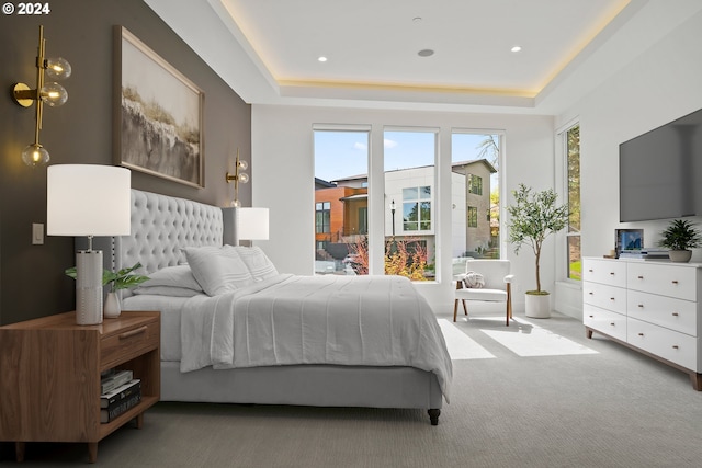 bedroom with light carpet and a tray ceiling