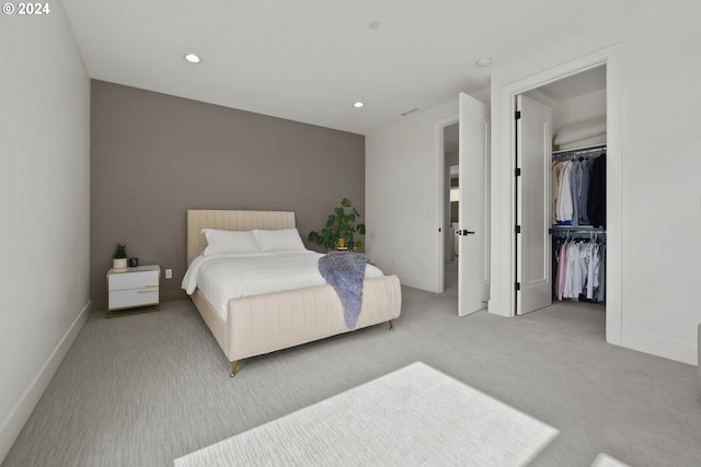 bedroom featuring a walk in closet, light colored carpet, and a closet