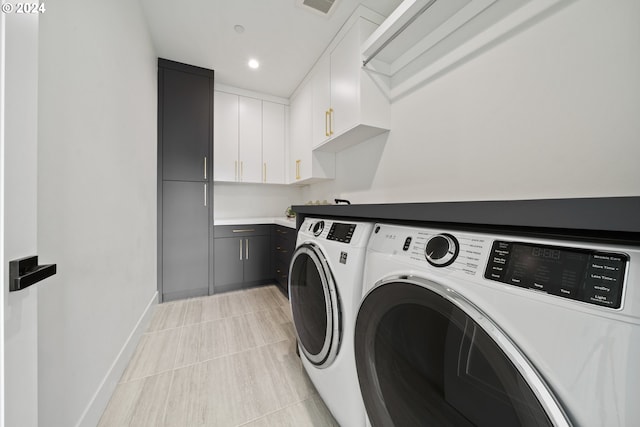 washroom featuring cabinets, light tile patterned floors, and washing machine and dryer