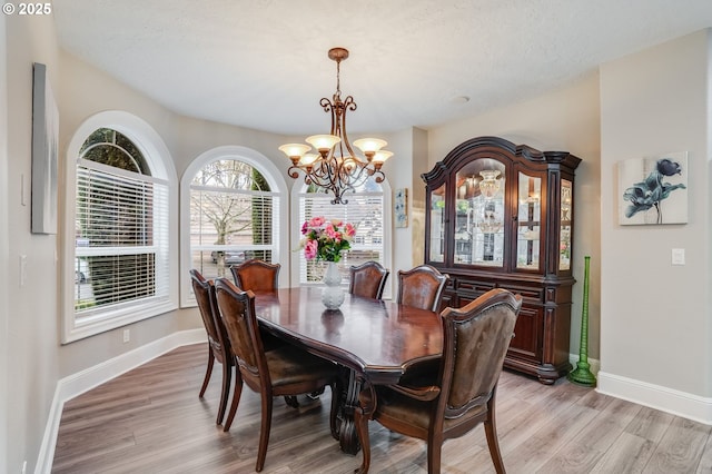 dining room with light hardwood / wood-style flooring and an inviting chandelier