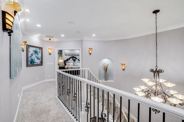 hall featuring carpet, crown molding, and a notable chandelier