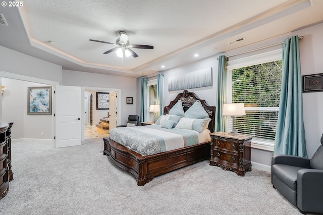 bedroom with a raised ceiling, ceiling fan, light carpet, and a textured ceiling