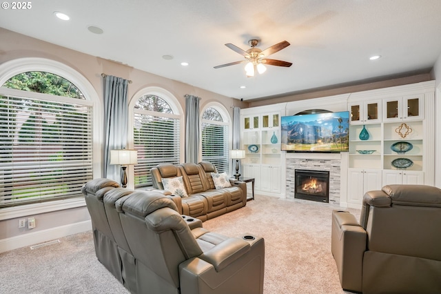 carpeted living room with a tile fireplace and ceiling fan