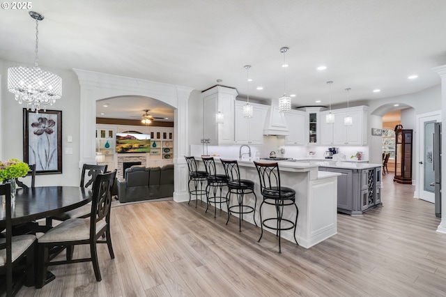 kitchen with white cabinets, pendant lighting, ceiling fan with notable chandelier, and a fireplace