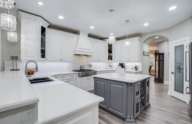 kitchen with custom exhaust hood, sink, gray cabinets, decorative light fixtures, and white cabinetry