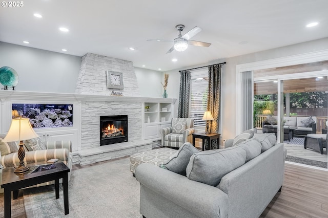 living room featuring ceiling fan, light hardwood / wood-style floors, built in features, and a fireplace