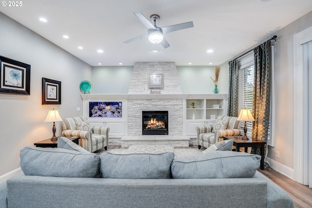 living room featuring a fireplace, built in shelves, light hardwood / wood-style flooring, and ceiling fan