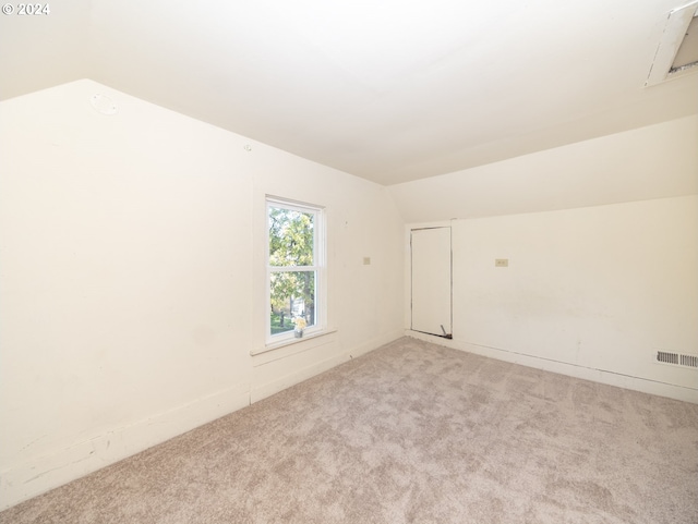 unfurnished room with light colored carpet and lofted ceiling