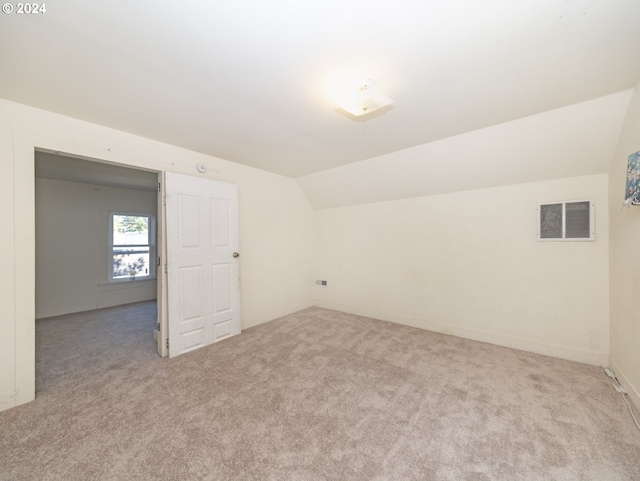 additional living space with light colored carpet and vaulted ceiling