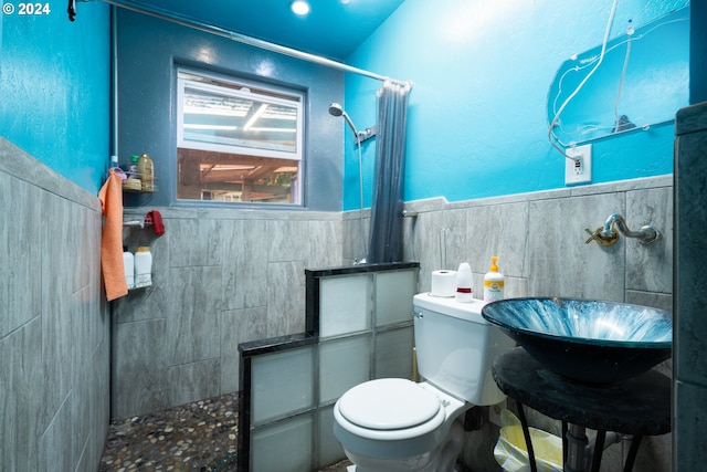 bathroom featuring tile walls, sink, a shower with shower curtain, and toilet