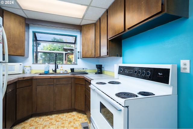 kitchen featuring white appliances, a drop ceiling, and sink