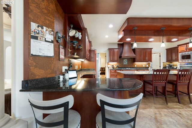 kitchen with sink, appliances with stainless steel finishes, decorative light fixtures, custom range hood, and decorative columns