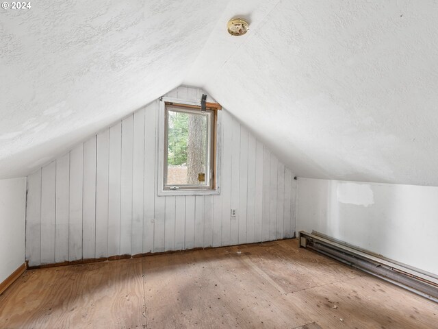 bonus room featuring a textured ceiling, vaulted ceiling, and a baseboard radiator