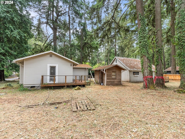 rear view of house with a storage unit and a wooden deck